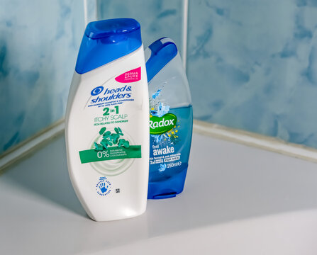Norwich, Norfolk, UK - November 29 2020. An illustrative editorial photo of a bottle of Head and Shoulders 2 in 1 hair shampoo and conditioner and Radox shower gel on the side of a white bath