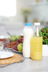 Close up of bottles of milk and orange juice served with Latin American breakfast on the table in modern kitchen interior