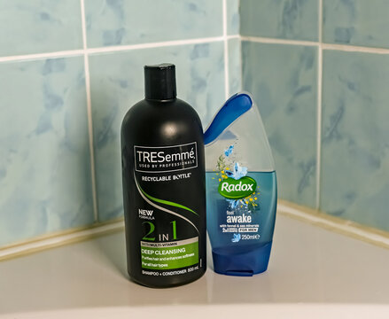Norwich, Norfolk, UK - November 29 2020. An illustrative editorial photo of a bottle of TRESemme 2 in 1 hair shampoo and conditioner and a bottle of Radox shower gel on the side of a white bath