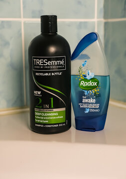 Norwich, Norfolk, UK - November 29 2020. An illustrative editorial photo of a bottle of TRESemme 2 in 1 hair shampoo and conditioner and a bottle of Radox shower gel on the side of a white bath