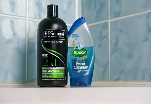 Norwich, Norfolk, UK - November 29 2020. An illustrative editorial photo of a bottle of TRESemme 2 in 1 hair shampoo and conditioner and a bottle of Radox shower gel on the side of a white bath