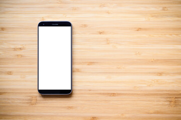 A smartphone with a blank display lies on an old wooden background.