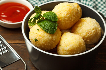Arancini, a dish of Italian and Sicilian cuisine, balls of rice and cheese with different fillings.Close-up in a black bowl
