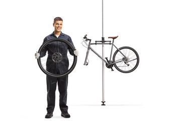 Bicycle repairman with a wheel and a bicycle for repair hanging on a stand
