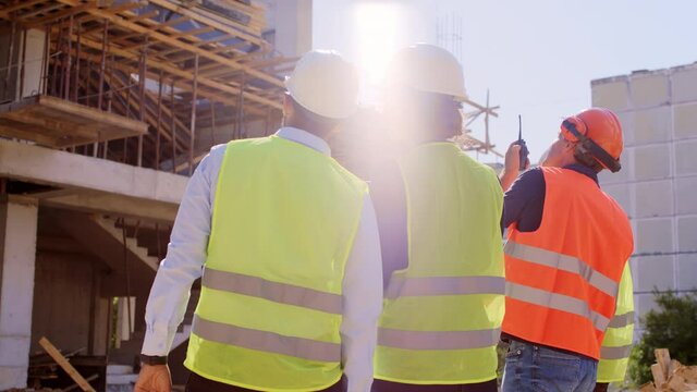 Young engineer and architect analyzing with the foreman the plan of construction site they looking concentrated to the building and continue to analyzing they wearing safety helmets and goggles