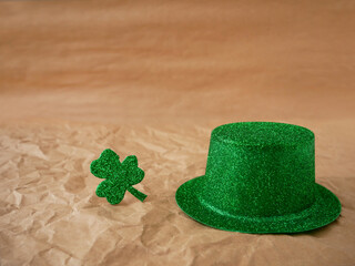 St. Patrick's day. The holiday symbol is a Green hat and a leaf of clover on a background of craft...