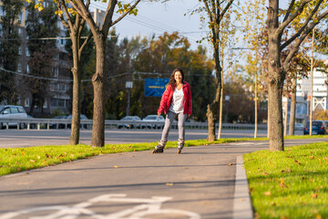 Active leisure. A sportive girl is rollerblading in an autumn park