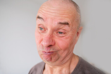 face of a European old man close up, wrinkles on the aging skin, bares teeth, makes grimaces, the concept of mental health, cosmetology, age-related changes