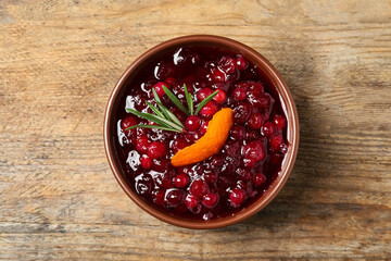 Cranberry sauce with orange peel and rosemary on wooden table, top view