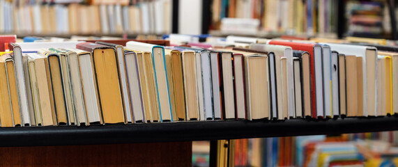 Row of many old used books displayed at local antiquarian bookshop, wide photo focus on right side