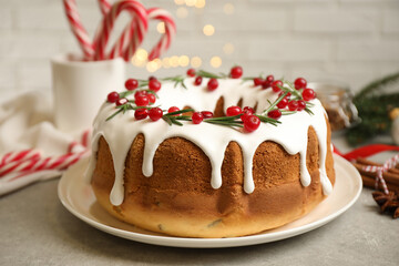 Traditional Christmas cake with cranberries, pomegranate seeds and rosemary on light grey table