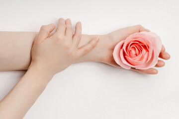 Beautiful hands of a woman holding a rosebud lying on a white background. concept of skin care, moisturizing and reducing wrinkles
