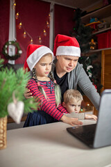 Safe online Christmas. Happy family in Santa red hats celebrating virtually via internet