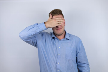 Business young man wearing a casual shirt over white background serious and covering her eyes with her hand