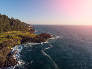 Fototapeta na wymiar Aerial drone panoramic view of rocks in the ocean. Rocky coast with green plants. Ocean waves. Amazing natural landscape. view from above.