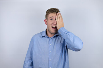 Business young man wearing a casual shirt over white background covering one eye with hand,...