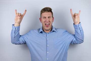 Business young man wearing a casual shirt over white background shouting with crazy expression doing rock symbol with hands up