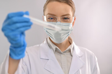 Macro shot of doctor or microbiologist in protective glasses, gloves and mask with biological tube on white laboratory background. Research and development concept. News feed.