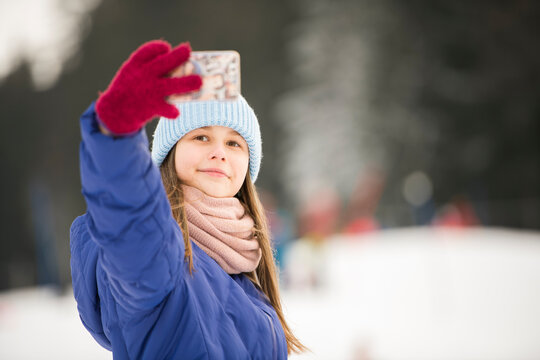 Adorable jeune fille prend des photos de selfie dans un magnifique parc d'hiver. Activit&eacute;s d'hiver pour les enfants.

