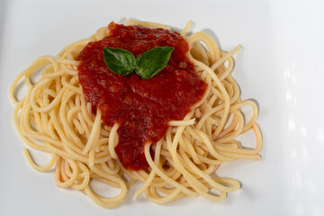 a portion of spaghetti pasta with red sauce on a white silver photographed in close up