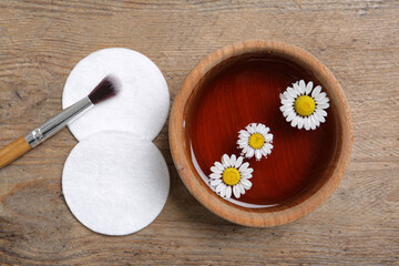 Flat lay composition with chamomile flowers and herbal infusion on wooden table
