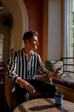 Caucasian man. Young Italian in a cafe at a table with his mobile phone. Stylish man in a coffee shop.