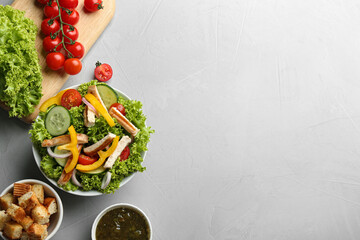 Fototapeta na wymiar Delicious chicken salad and fresh vegetables on grey table, flat lay. Space for text