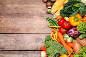 Different fresh vegetables on wooden table, flat lay. Space for text