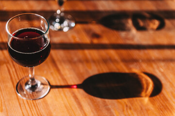 Glass of red wine on the table with shadow from side sun rays