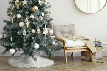Beautiful decorated Christmas tree with skirt in room