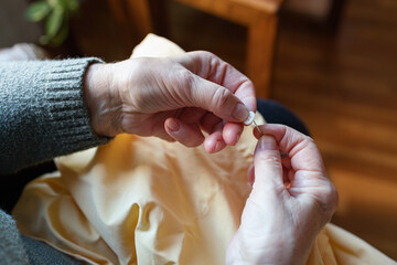 Old woman sewing a button at home