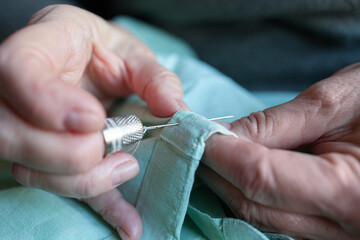 Close-up of old woman sewing at home