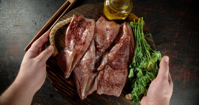 A wooden tray with raw squid is put on the table.