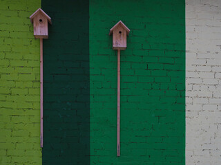 Birdhouses on a textured background of a multi-colored painted brick wall.