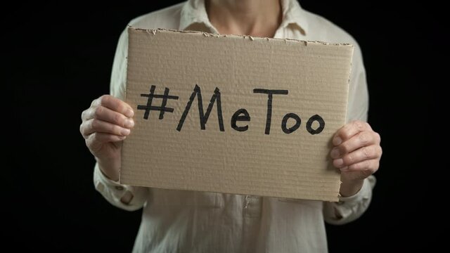 Metoo activist. A woman hold a poster with words metoo in support of the movement on the black background.
