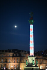 Stuttgart monument Jubiläumssäule in Christmas lighting decoration at night with cloudless clear sky and full moon, red hearts on the column