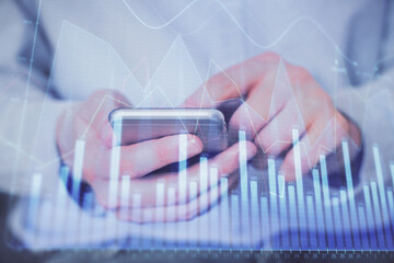 Double exposure of man's hands holding and using a digital device and forex graph drawing. Financial market concept.