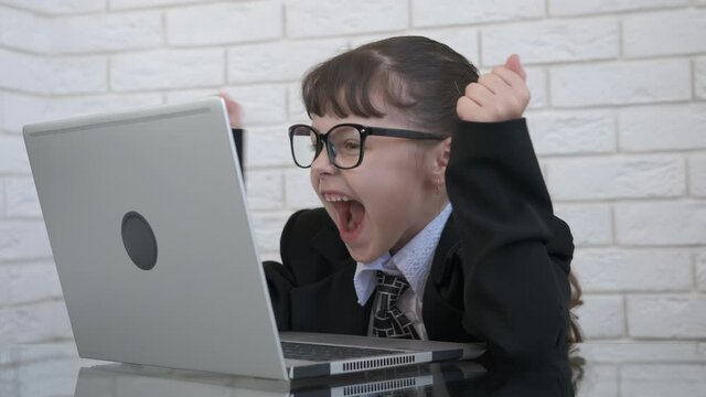 Child business plan. A child in a suit chatting on computer and start to smile in the room.