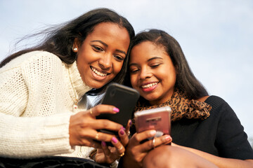 Close up os two black girls on some stairs in a city while they are watching something interesting...