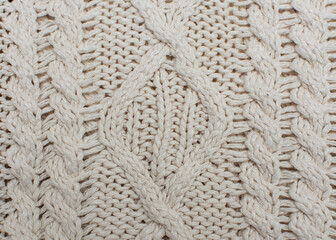 Knitted background, texture, pattern. Closeup of sample with knitting weave. Cable knitting.