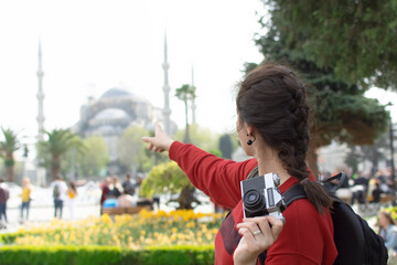 Tourist Woman with backpack and camera taking photo in front of Blue Mosque in Sultanahmet square...