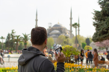 Tourist man with camera taking photo in front of Blue Mosque in Sultanahmet square Istanbul. Travel...