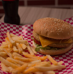 Hamburguesa de pollo apanado y papas fritas en la canasta sobre estampado rojo y blanco