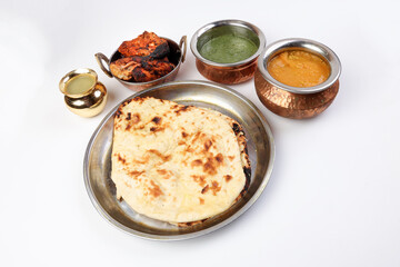 Spicy red Chicken grilled tikka tandoori nan bread green spinach curry yogurt sauce dal tomato cucumber onion salad set in metal stainless steel brass copper pot on white background
