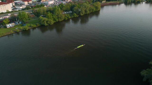 Aerial view of a group of people canoeing on the Main river, on the coast of the Raunheim village, sunny evening, in Germany - pull back, drone shot