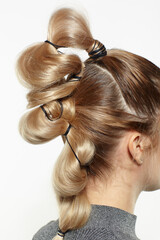 back view portrait of blonde female with creative braid hairdo.