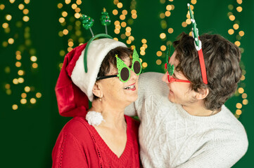 Selective focus. Grandson and grandmother happy smiling in a Christmas glasses on a green background. Merry Christmas and happy new year concept.
