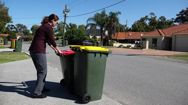 Adult woman household taking out bin to the street on rubbish day.