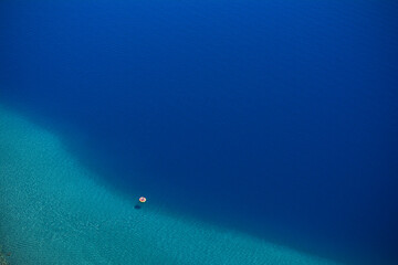 blue waters seen from above with a small boat in the immensity of a lake with turquoise shores