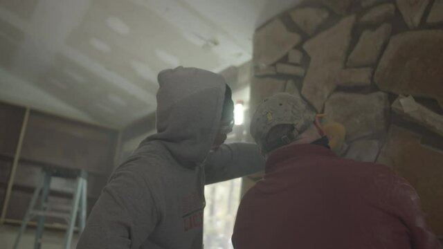 Young construction worker is pointing at the fireplace